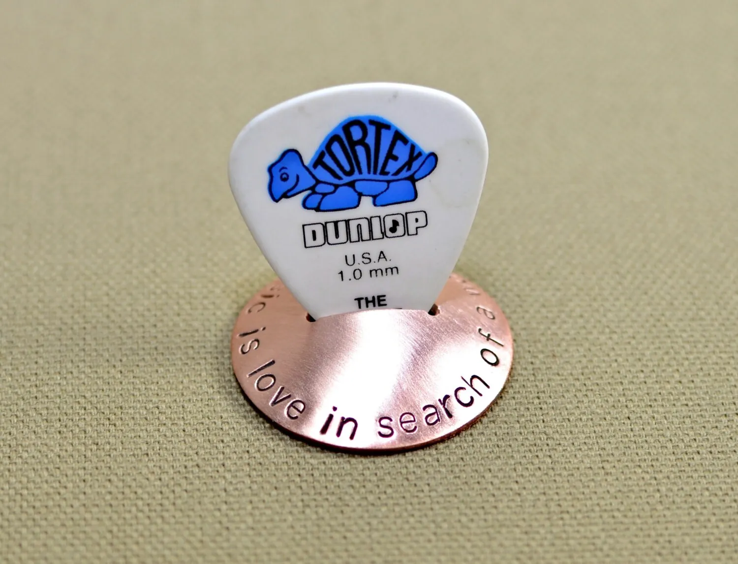 Copper guitar pick stand with "music is love in search of a word