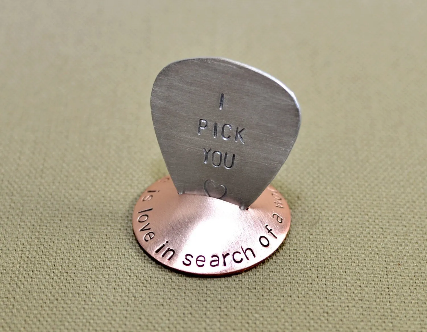 Copper guitar pick stand with "music is love in search of a word