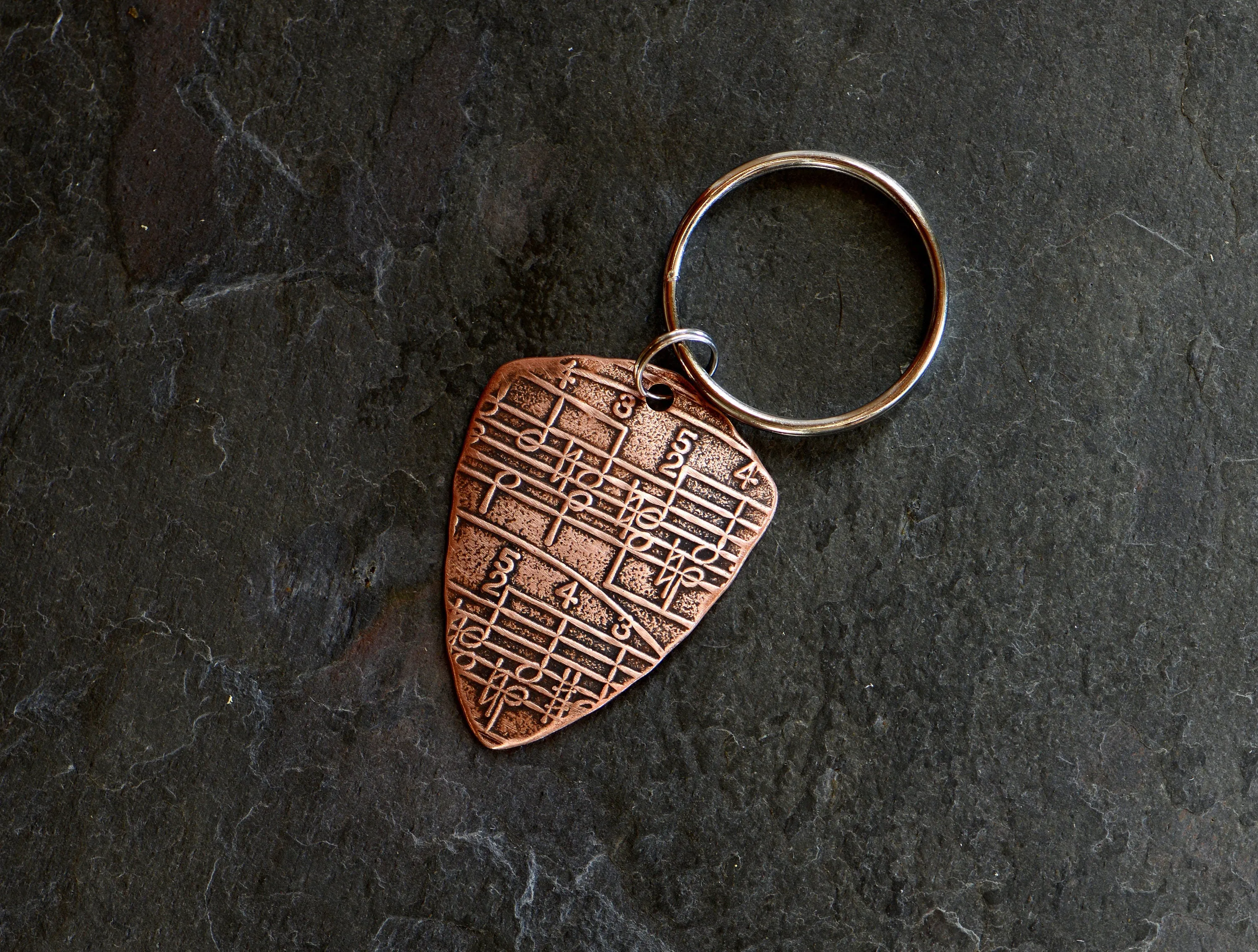 Copper key ring guitar pick with music notes