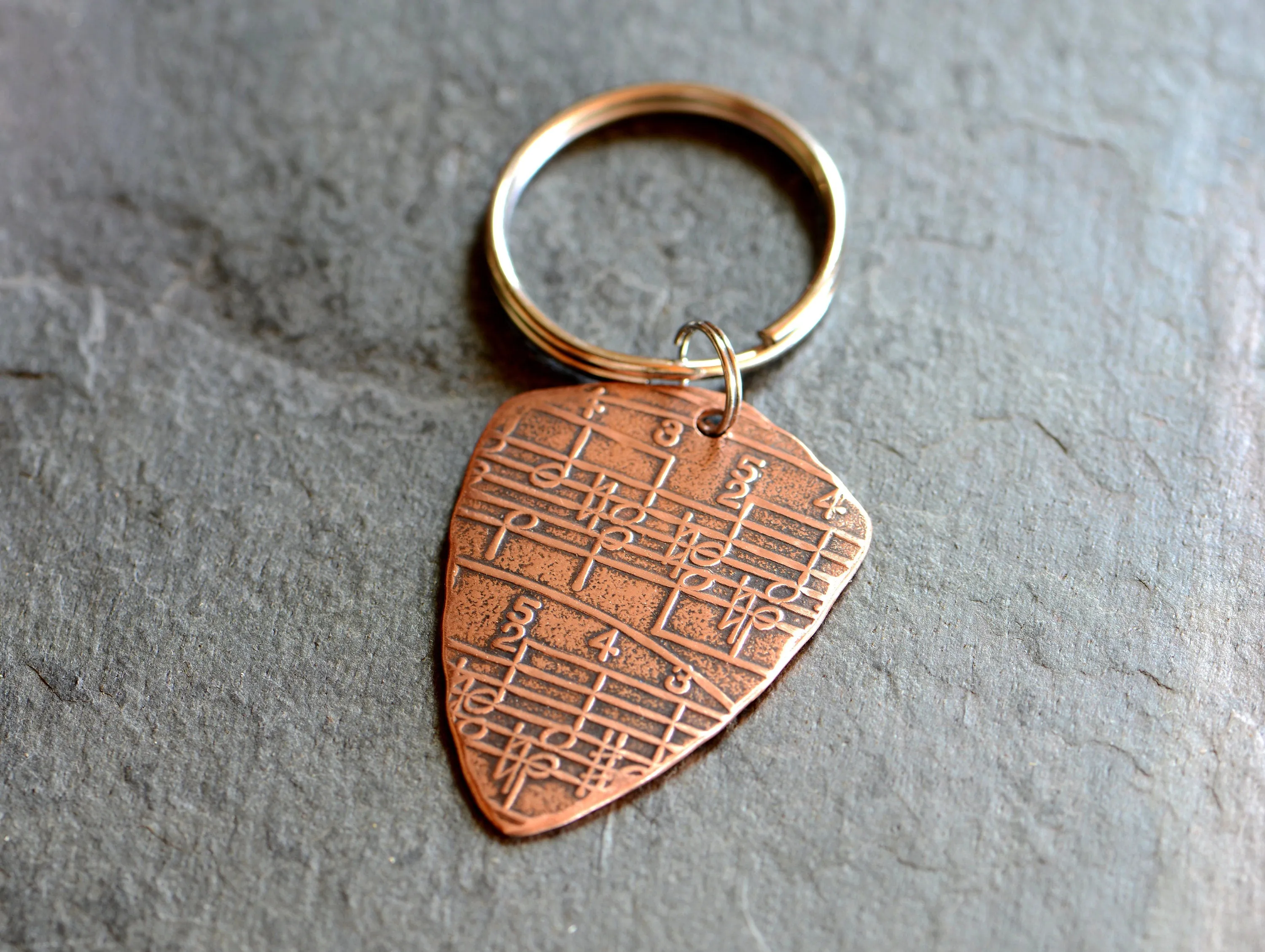Copper key ring guitar pick with music notes