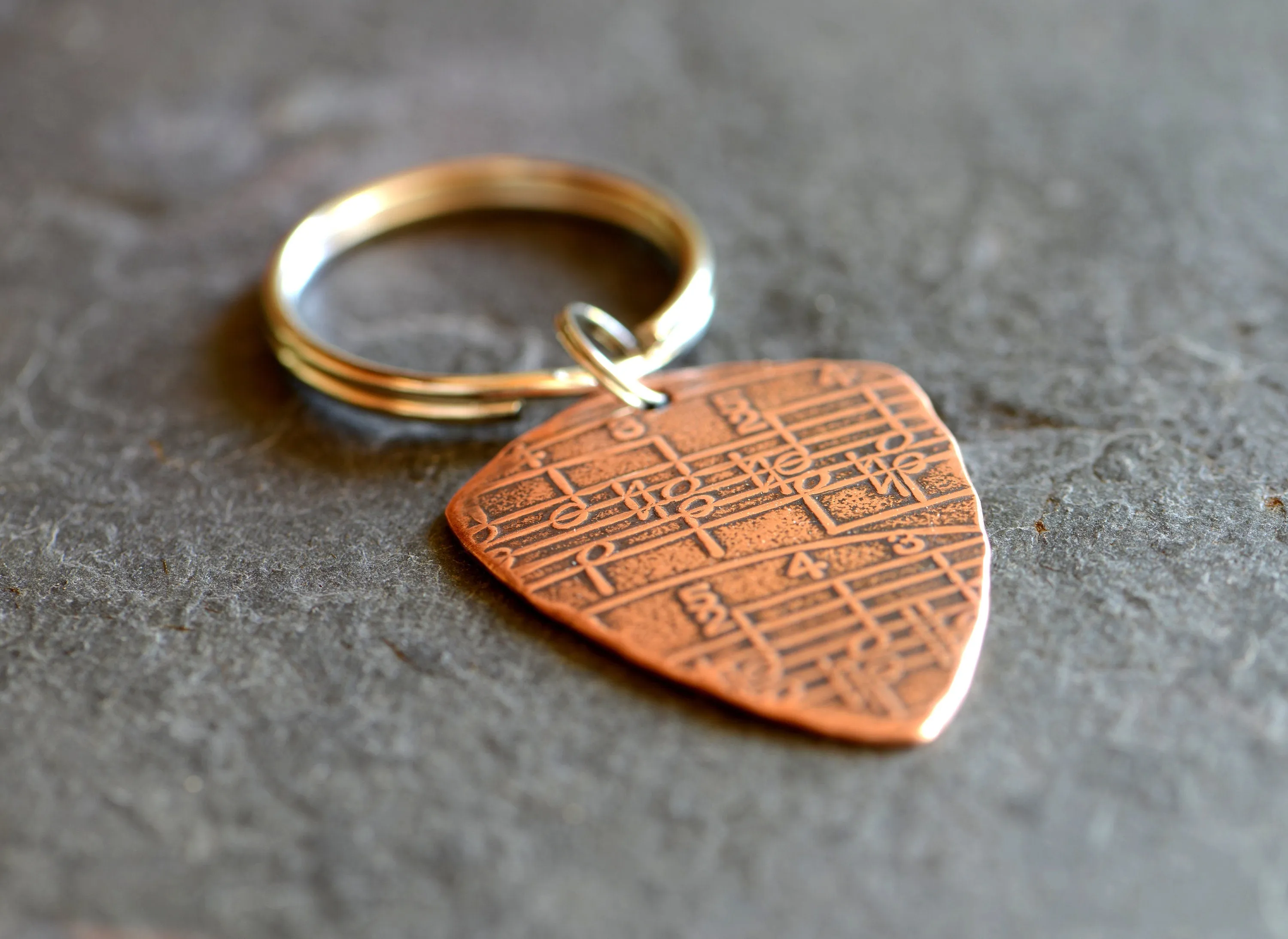 Copper key ring guitar pick with music notes