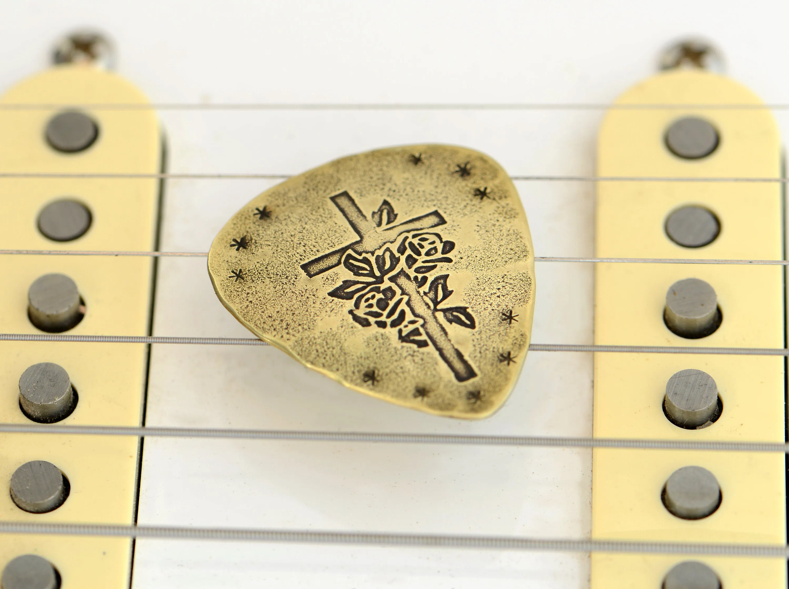 Playable brass guitar pick with cross and roses