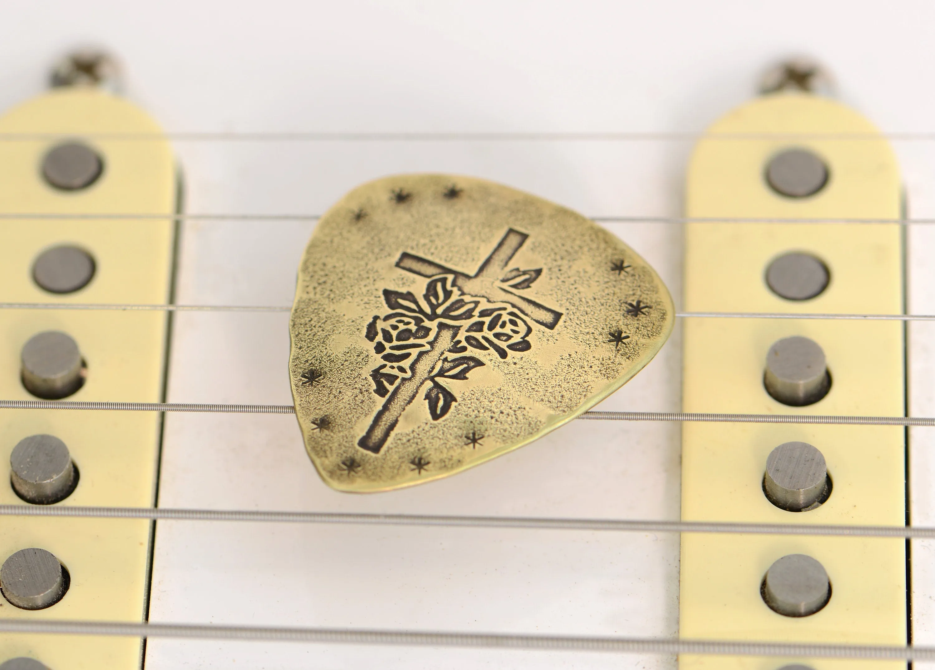Playable brass guitar pick with cross and roses