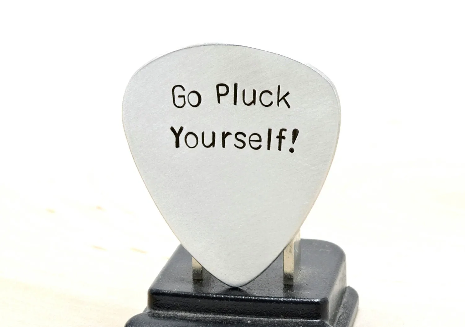 Silver guitar pick with Go Pluck Yourself