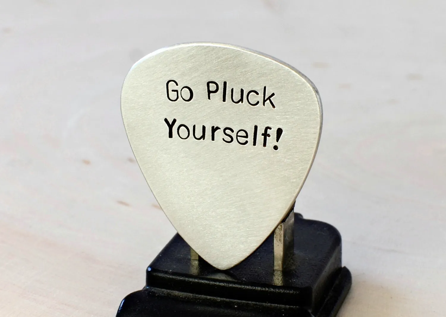 Silver guitar pick with Go Pluck Yourself