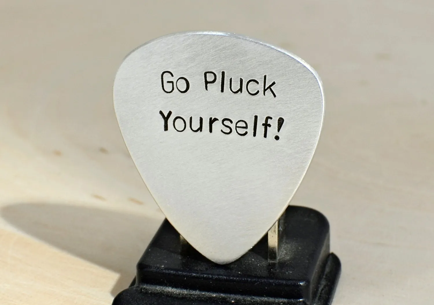 Silver guitar pick with Go Pluck Yourself